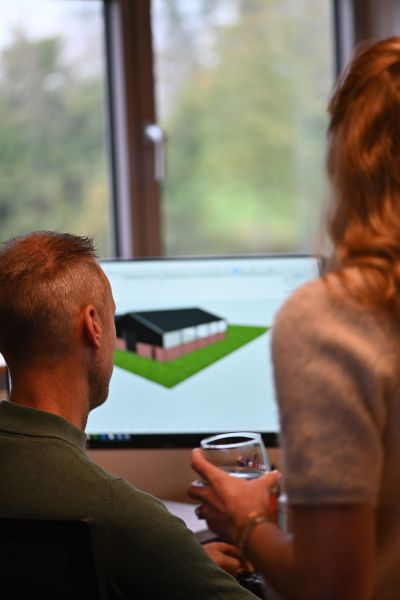 Twee collega’s bekijken een 3D-model van een woningontwerp op de computer bij Van Wiggen Bouw in Vianen