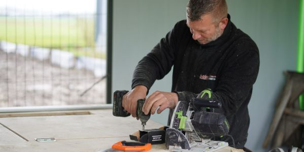 Voorman van Van Wiggen Bouw boort en zaagt hout op de bouwplaats tijdens de uitvoering van een bouwproject in Vijfheerenlanden