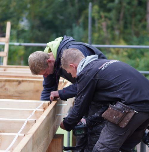Voorman en timmerman van Van Wiggen Bouw werken samen aan houten constructie op de bouwplaats