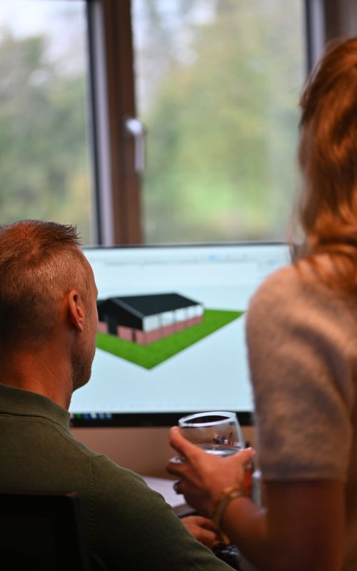 Twee collega’s bekijken een 3D-model van een woningontwerp op de computer bij Van Wiggen Bouw in Vianen
