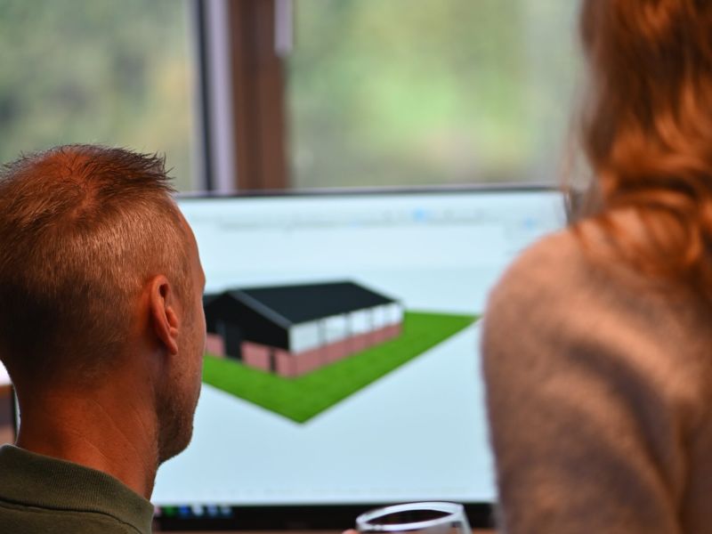 Twee collega’s bekijken een 3D-model van een woningontwerp op de computer bij Van Wiggen Bouw in Vianen
