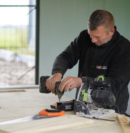 Voorman van Van Wiggen Bouw boort en zaagt hout op de bouwplaats tijdens de uitvoering van een bouwproject in Vijfheerenlanden