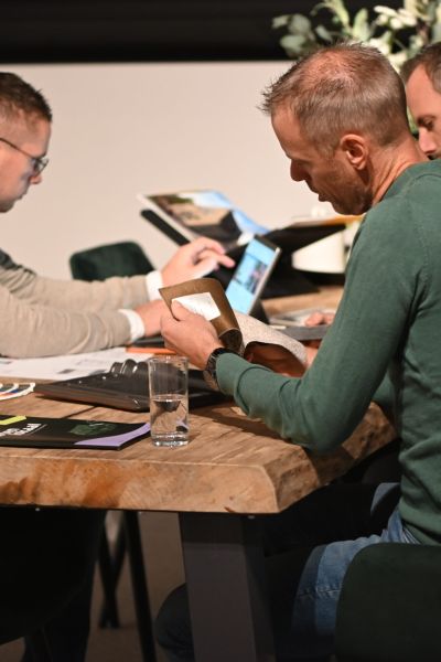 Drie medewerkers van Van Wiggen Bouw bespreken bouwmaterialen en ontwerpen aan tafel in de showroom in Vianen